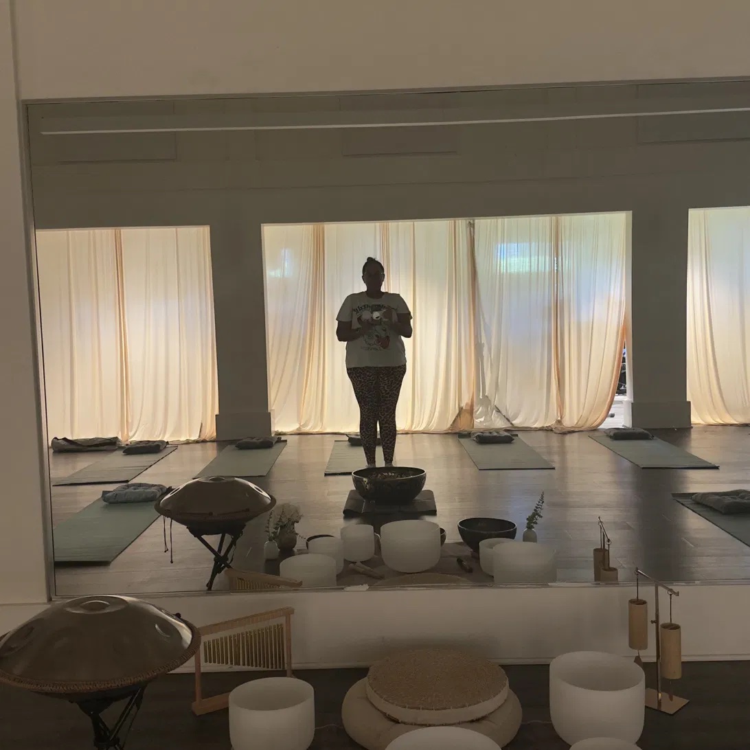 Silhouette of Patrice standing over singing bowls during a sound healing session